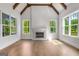 Bright living room with vaulted ceiling, exposed wood beams, fireplace, and large windows overlooking lush greenery at 100 Regina Ct, Fayetteville, GA 30215