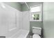 Bright bathroom featuring a shower-tub combo and toilet next to a window at 810 Bedford Park, Peachtree City, GA 30269