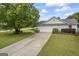 View of long driveway leading to attached two-car garage, surrounded by well-maintained lawn and mature trees at 301 Bradford Ct, Auburn, GA 30011