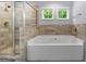 Bathroom featuring a soaking tub, glass enclosed shower, and stone tiling at 8 Saint Charles Ave, Sharpsburg, GA 30277