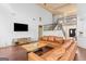 Open-concept living room featuring a staircase, TV, and a comfortable brown leather couch at 1202 Persimmon Way, Mcdonough, GA 30252
