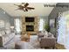 Virtual staged living room features a stone fireplace, ceiling fan, and matching grey furniture at 8846 Wesley Pl, Jonesboro, GA 30238