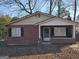 Charming brick home with a covered front porch and black shutters, surrounded by trees at 953 South Ave, Forest Park, GA 30297