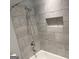Bathroom features grey tile with a shower head, bathtub, and convenient niche at 6884 Shangrila Way, Riverdale, GA 30296