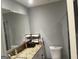 A well lit bathroom with a granite counter and a storage rack at 6884 Shangrila Way, Riverdale, GA 30296