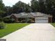 Charming red brick home featuring a paved driveway, two-car garage, solar panels, and lush front lawn at 2958 Mary Alice Trl, Loganville, GA 30052