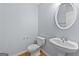Cozy half bathroom with a pedestal sink, oval mirror, and modern toilet at 695 Georgetown Ct, Jonesboro, GA 30236
