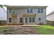 View of the backyard showing beige siding, multiple windows, and a small concrete patio at 2093 Parador Bnd, Mcdonough, GA 30253