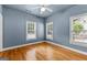 Bedroom with blue walls, three windows with blinds, ceiling fan, and wood flooring at 285 Spear Rd, Peachtree City, GA 30269