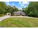 Expansive front yard featuring a circular driveway leading to a charming home nestled among lush trees and greenery at 285 Spear Rd, Peachtree City, GA 30269