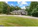 Expansive front yard featuring a circular driveway leading to a charming home nestled among lush trees and greenery at 285 Spear Rd, Peachtree City, GA 30269