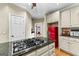 Well-equipped kitchen with island cooktop, granite countertops, stainless appliances, and a vintage red refrigerator at 285 Spear Rd, Peachtree City, GA 30269