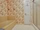 Classic bathroom with a tub and shower, featuring floral wallpaper and tile flooring at 550 Hawthorne Dr, Fayetteville, GA 30214
