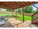 Covered patio area with brick pavers, retaining wall and steps leading to the well manicured backyard at 910 Pebble Creek Trl, Suwanee, GA 30024