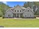 Charming two-story home featuring a stone facade, gray siding, well-manicured lawn, and welcoming front porch at 33 Vinery Ct, Sharpsburg, GA 30277