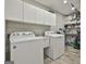 Well-organized laundry room with white washer, dryer, sink, cabinets, shelving and tile flooring at 505 Bracken Edge, Peachtree City, GA 30269