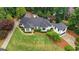 Stunning home featuring a lush lawn, manicured shrubs, and a dark gray roof surrounded by mature trees at 4030 River Ridge Chase Se, Marietta, GA 30067