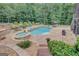 Backyard swimming pool and spa with stone accents, surrounded by lush greenery and patio furniture at 265 Beverly Farms Dr, Sharpsburg, GA 30277