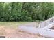 Backyard view featuring a retaining wall and staircase with surrounding trees at 3858 Trenton Dr, Snellville, GA 30039