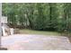 Large concrete patio space leading to a spacious backyard filled with mature trees and greenery at 3858 Trenton Dr, Snellville, GA 30039