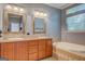 Bathroom with double sinks, wood cabinets, tile flooring, soaking tub and neutral paint at 315 Jewel Ln, Covington, GA 30014