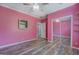 Pink bedroom with wood floors, ceiling fan, view of closet and an arched doorway at 315 Jewel Ln, Covington, GA 30014