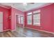 Pink bedroom featuring wood floors, ceiling fan, three windows and mirrored closet at 315 Jewel Ln, Covington, GA 30014