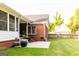 Backyard patio area with brick accents, a screened-in porch, and a view of the well-maintained lawn and garden area at 30 Carolyn Ct, Social Circle, GA 30025