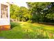 View of the spacious backyard featuring a large green lawn, mature trees, and a swing set, perfect for outdoor activities at 30 Carolyn Ct, Social Circle, GA 30025