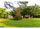 Charming brick home featuring a covered front porch and lush green lawn with mature trees at 30 Carolyn Ct, Social Circle, GA 30025