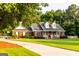 Charming brick home featuring a covered front porch and lush green lawn with mature trees at 30 Carolyn Ct, Social Circle, GA 30025