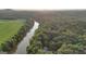 Breathtaking aerial view showcasing a lush, wooded property along a serene river and adjacent to a vast green field at 223 Old Rome Rd, Kingston, GA 30145