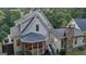 Back exterior of the home featuring a screened porch, outdoor seating, and beautiful landscaping with mature trees at 223 Old Rome Rd, Kingston, GA 30145