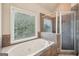A bathroom featuring a large jetted tub with a window view and a glass-enclosed shower is a relaxing oasis at 1979 Alcovy Shoals Blf, Lawrenceville, GA 30045