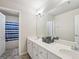 Well-lit bathroom featuring dual sinks, a large mirror, and a shower with blue curtain at 1979 Alcovy Shoals Blf, Lawrenceville, GA 30045