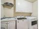 Bright laundry room featuring a utility sink, a washer, a dryer and white cabinets at 1979 Alcovy Shoals Blf, Lawrenceville, GA 30045