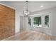 Dining room featuring a brick wall, modern light fixture, bay window, and light-colored wood floors at 90 Country Roads Cir, Stockbridge, GA 30281