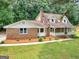 Charming brick home featuring a well-manicured lawn, mature trees, and a welcoming front porch at 90 Country Roads Cir, Stockbridge, GA 30281