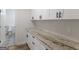 Bright laundry room features granite counters, ample cabinet space, and access to a half bathroom with stylish patterned floor tiles at 90 Country Roads Cir, Stockbridge, GA 30281