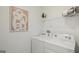 Neat laundry room with white washer and dryer, shelf storage, and modern art at 5451 Baybrook Cir, South Fulton, GA 30349