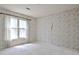 Cozy bedroom with neutral carpeting, wallpapered walls, and a large window draped with sheer curtains at 212 Garret Rdg, Peachtree City, GA 30269