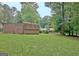 Backyard view showcasing a green lawn, a shed, and mature trees in a serene setting at 501 Bridlepath Ln, Peachtree City, GA 30269