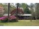 Brick home featuring flowering bushes and mature trees in a serene setting at 501 Bridlepath Ln, Peachtree City, GA 30269