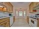 Traditional style kitchen featuring wood cabinets, white appliances and a dining nook with large windows and modern lighting at 501 Bridlepath Ln, Peachtree City, GA 30269