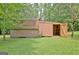 Side view of a brown shed with open doors in a green lawn surrounded by trees and some lawn lattice at 501 Bridlepath Ln, Peachtree City, GA 30269