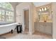 Bright bathroom features a freestanding tub beneath an arched window and a vanity with decorative mirror and fixtures at 135 Edgewater Trl, Fayetteville, GA 30215
