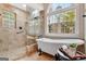 Bathroom featuring a soaking tub, tiled walk-in shower, and arched window offering natural light at 135 Edgewater Trl, Fayetteville, GA 30215