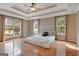 Spacious main bedroom with tray ceiling, fan, hardwood floors and multiple large windows at 135 Edgewater Trl, Fayetteville, GA 30215