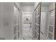 Hallway view of luxurious bathroom featuring white marble floors, tub, and mirrored closets at 108 Summit Walk, Peachtree City, GA 30269