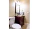Compact bathroom with a dark wood vanity, framed mirror, stylish fixtures, and a toilet at 8035 Magnolia Way, Roswell, GA 30075